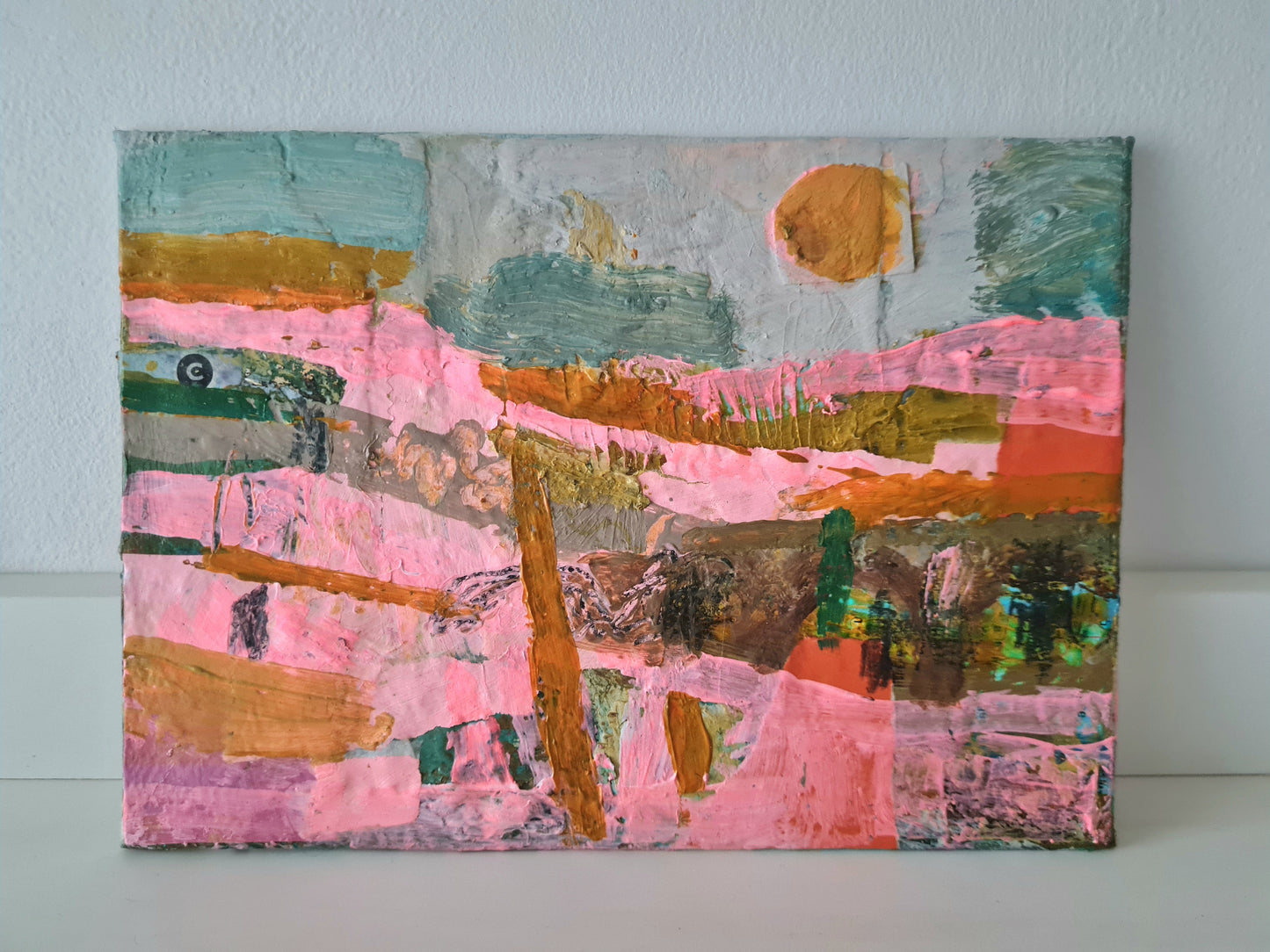 Abstract landscape painting with pink, orange, and green colours on a white wall.