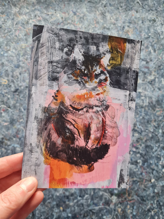 cat art greeting card held by a hand on a textured surface