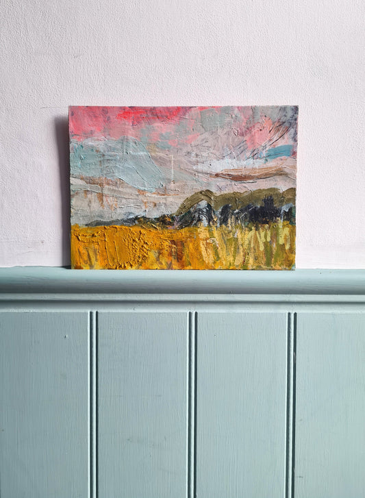Abstract landscape painting on a light blue surface with a white wall background