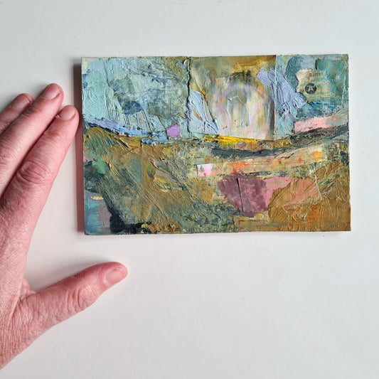 Abstract painting on a small board held by a hand against a white background