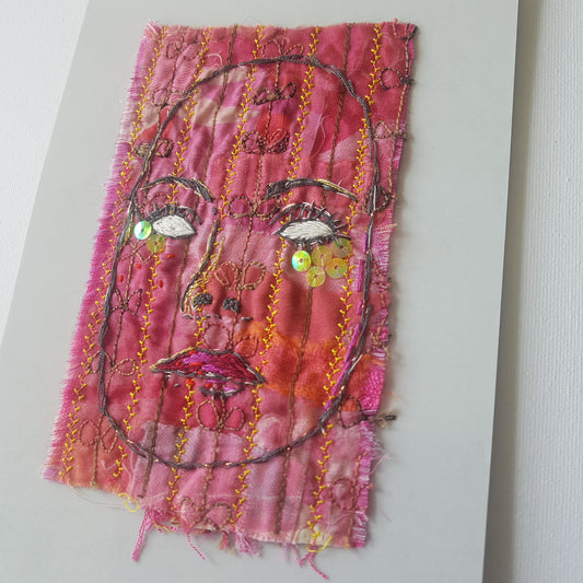 Textile artwork. Red embroidered face called Who is Behind the Mask?