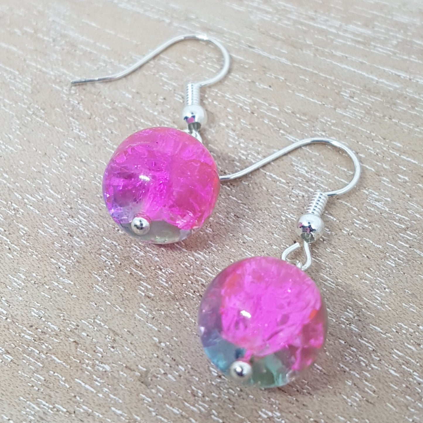 Close up of sparkly pink glass bead earrings on a wooden table.