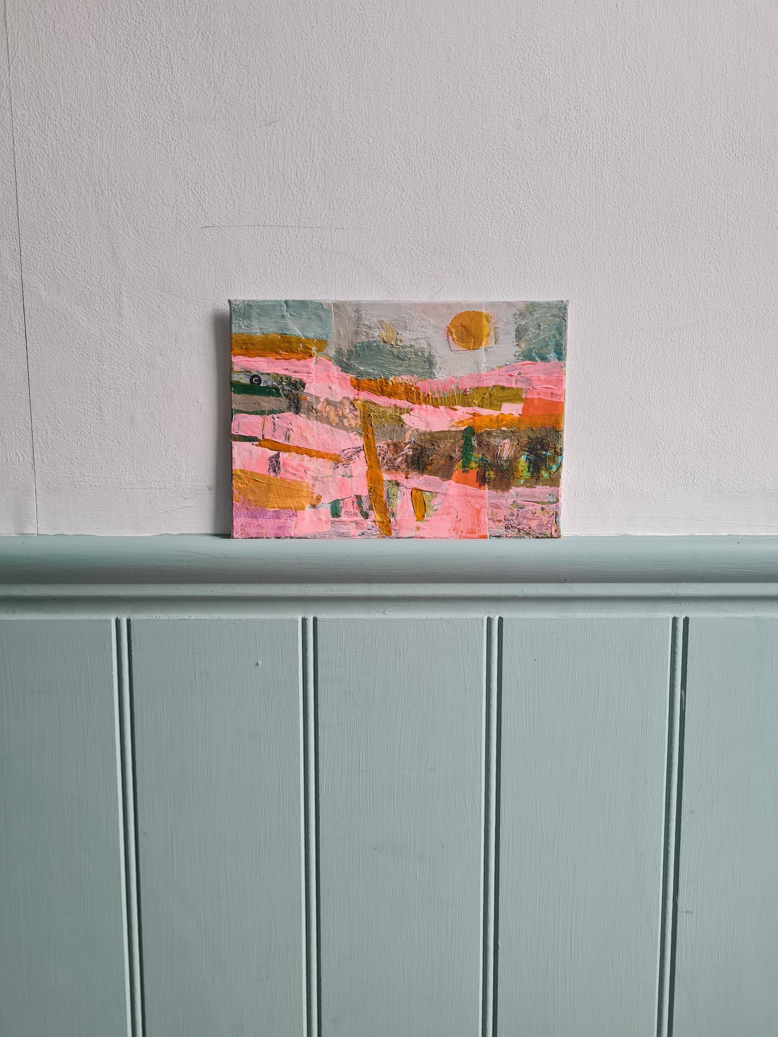Abstract painting on a white wall next pale blue woodwork