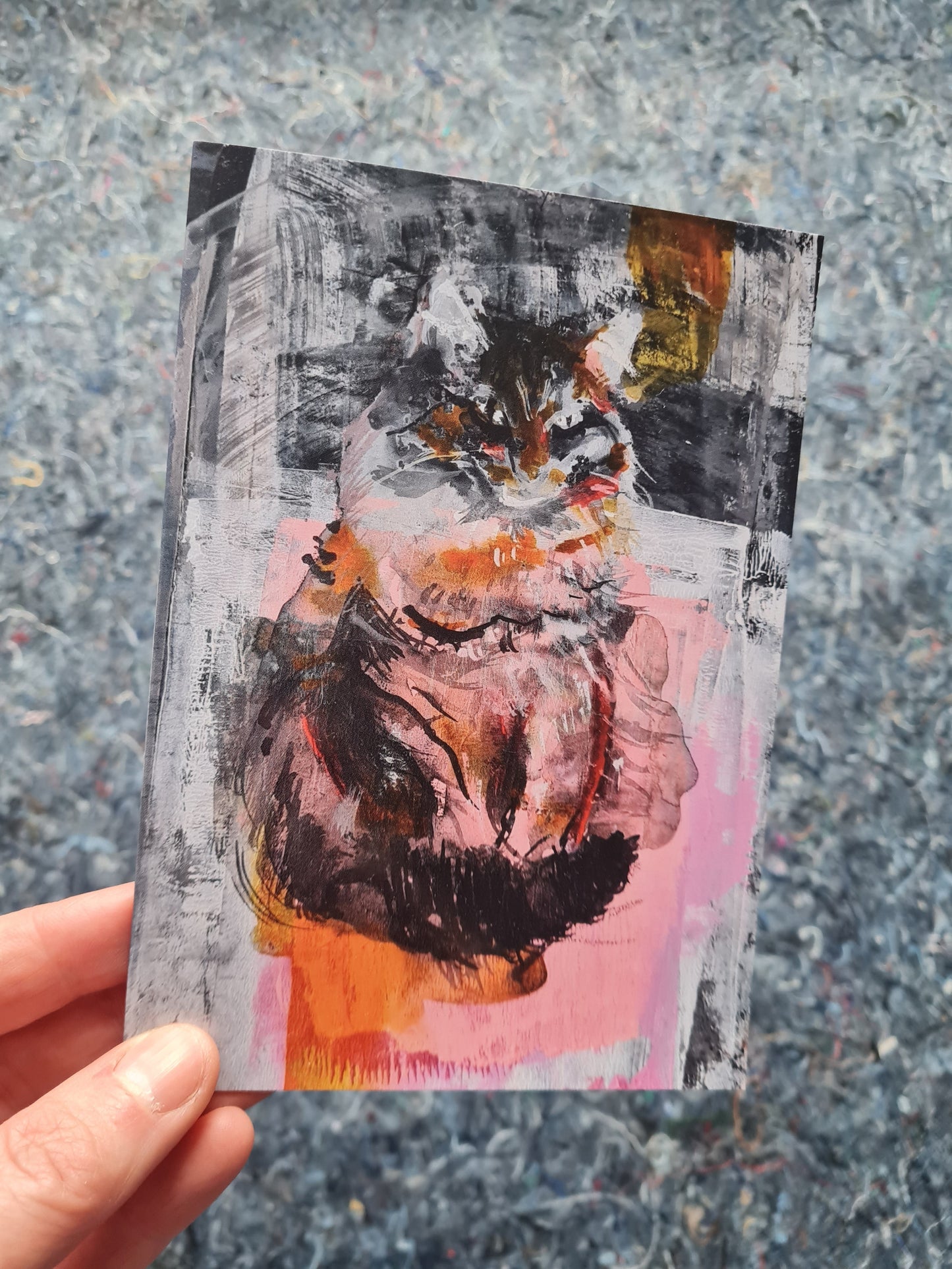 cat art greeting card held by a hand on a textured surface