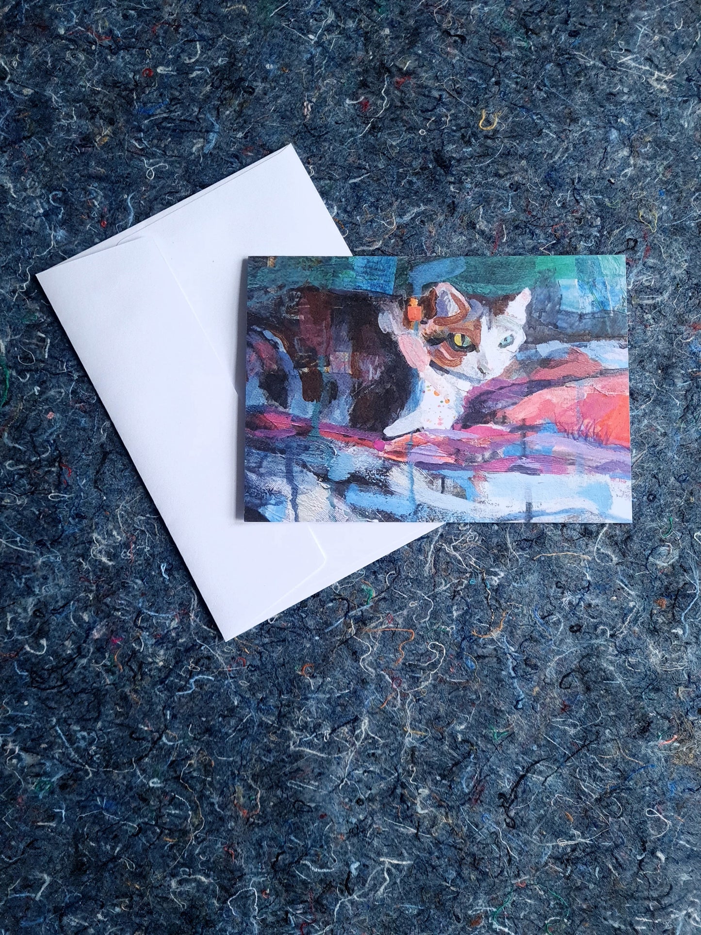 Greeting card featuring painting of a cat on a textured blue surface with a white envelope.