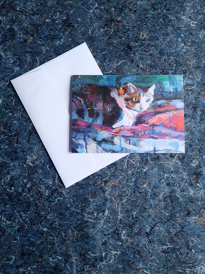 Greeting card featuring painting of a cat on a textured blue surface with a white envelope.