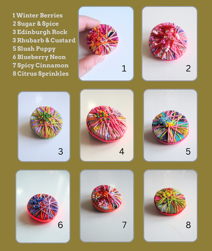 Colourful textured round brooches with names on a green background