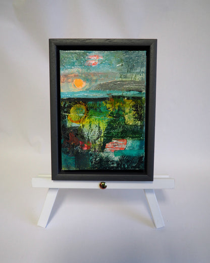 Small abstract landscape painting by Julia Laing, on a white tabletop easel against a white background.