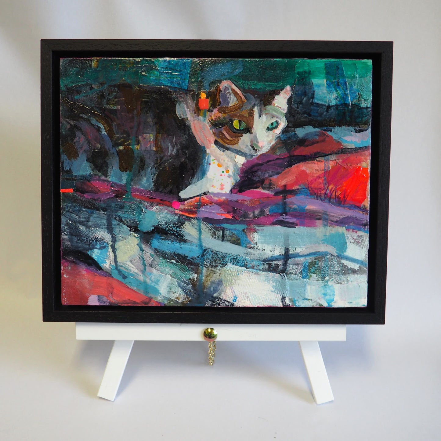 Framed cat painting Marco in the Evening Light by Julia laing on a white table top easel against a white background.