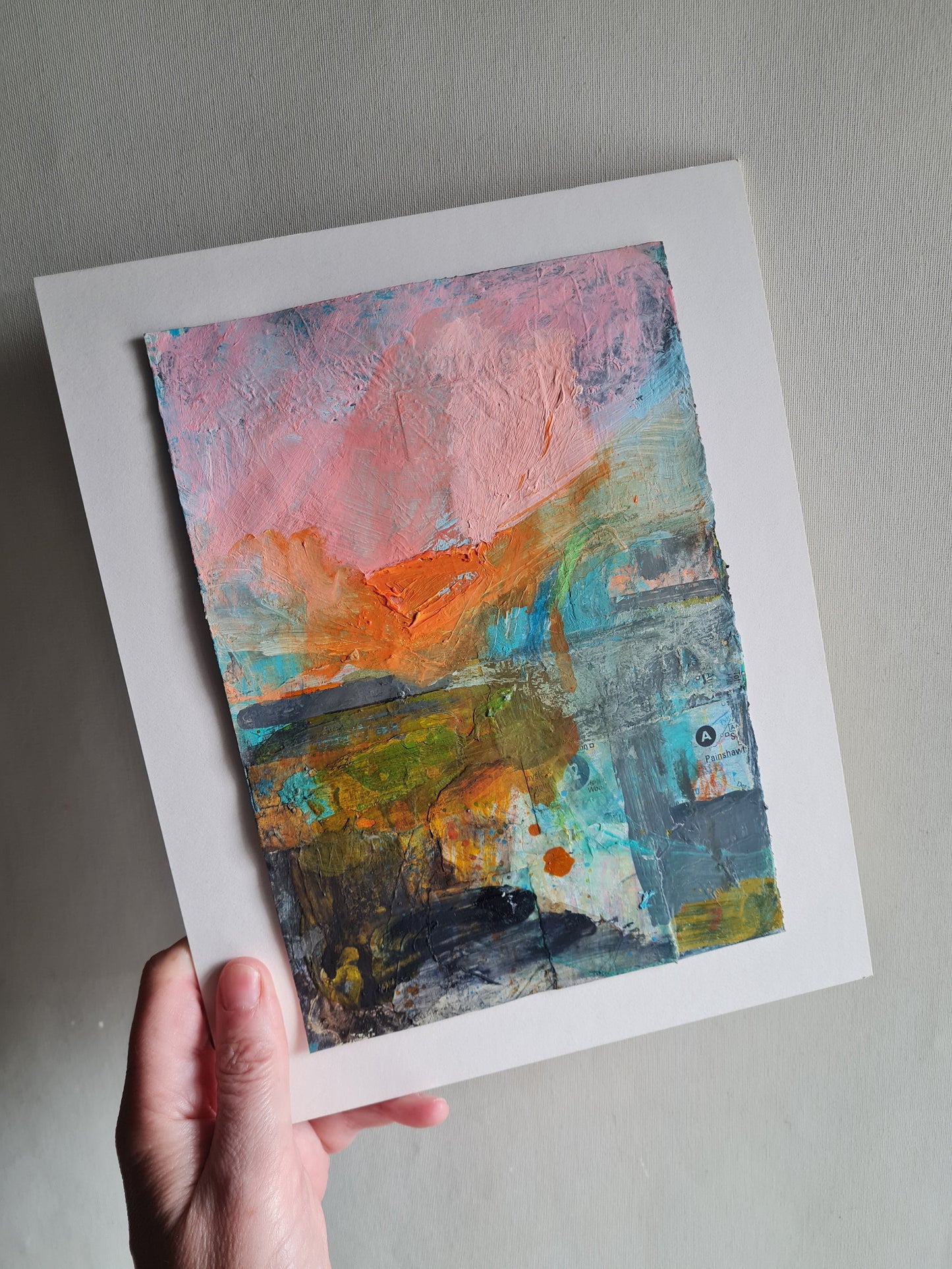 Abstract art painting held by a hand on a white background