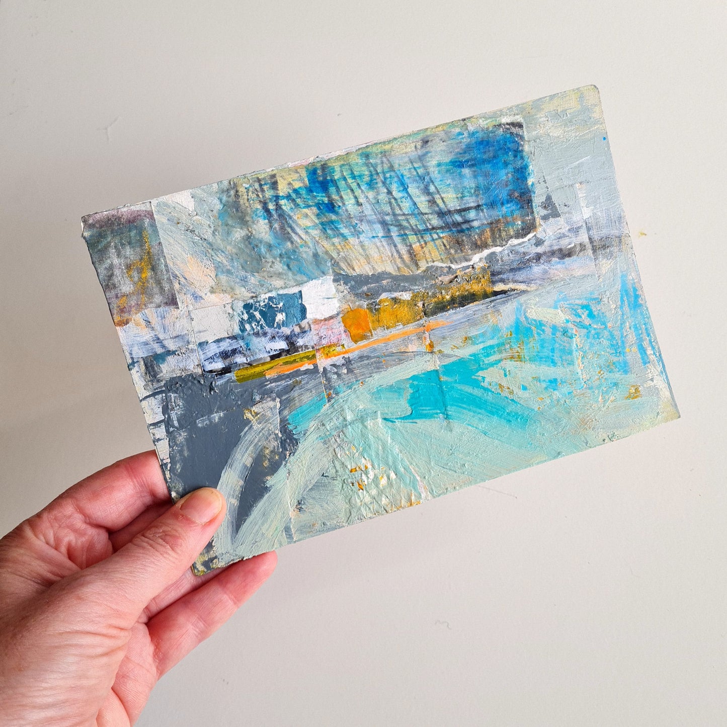 Abstract art piece held by a hand on a light gray background