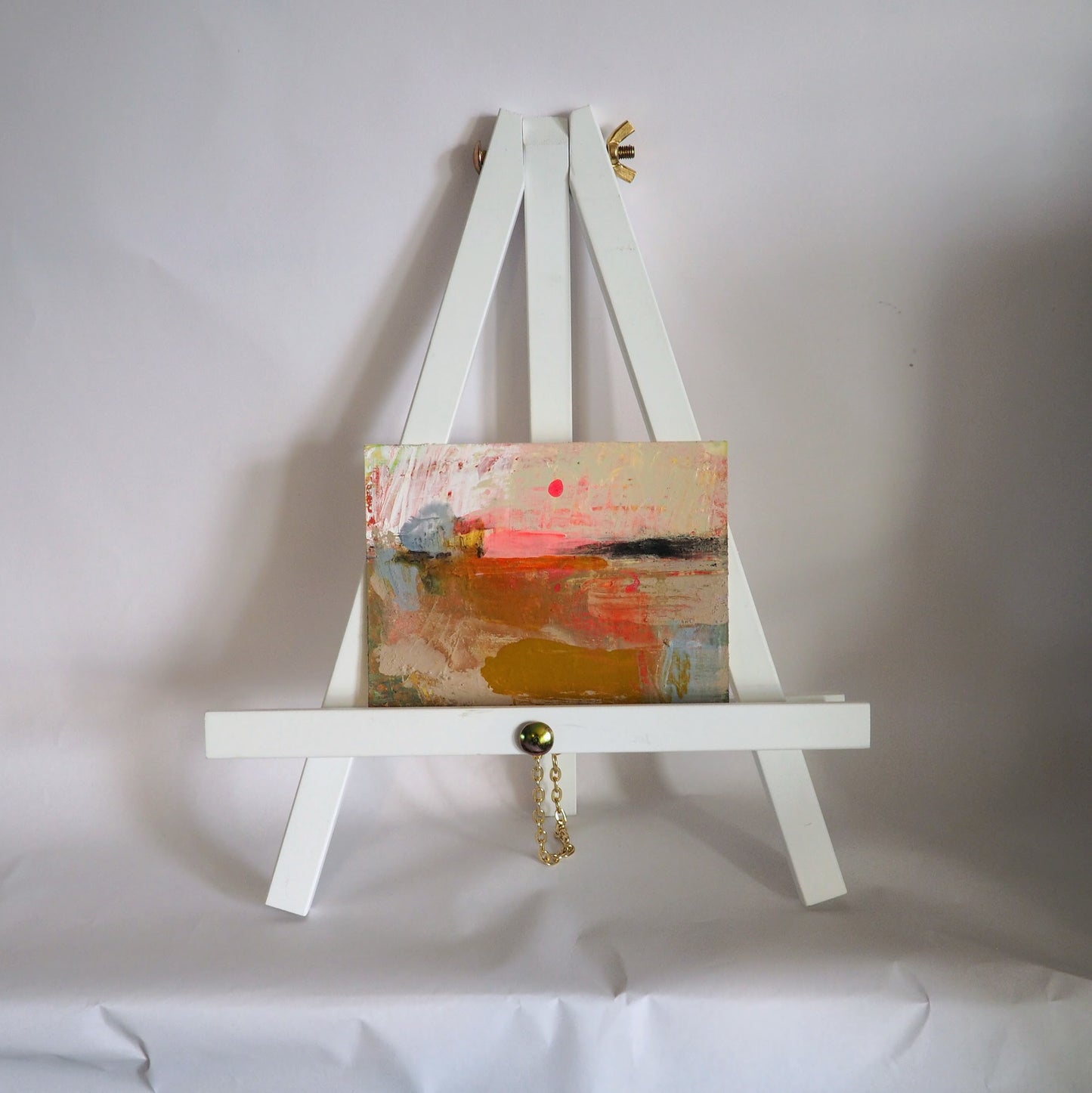 Mini abstract landscape painting by Julia Laing on a display easel with a white background.