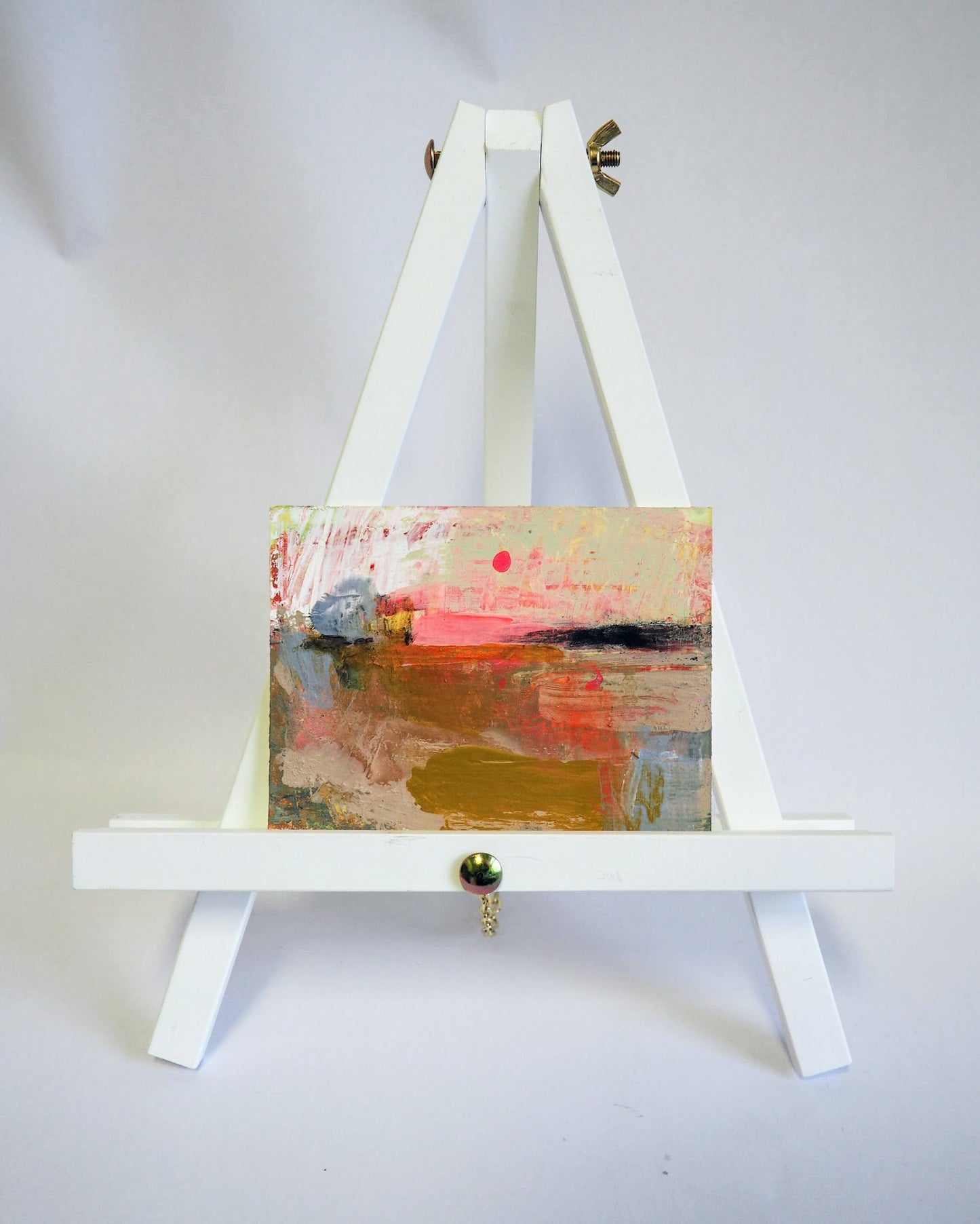 Small expressive abstract landscape painting, Pink Moon on a white display easel with a white background.