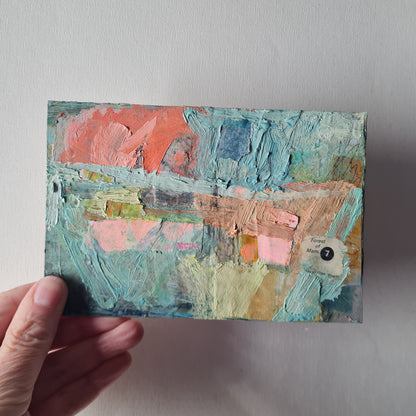 Hand holding a textured art piece with pastel colors on a neutral background