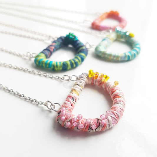 Textile art necklaces by Julia Laing on a white table.