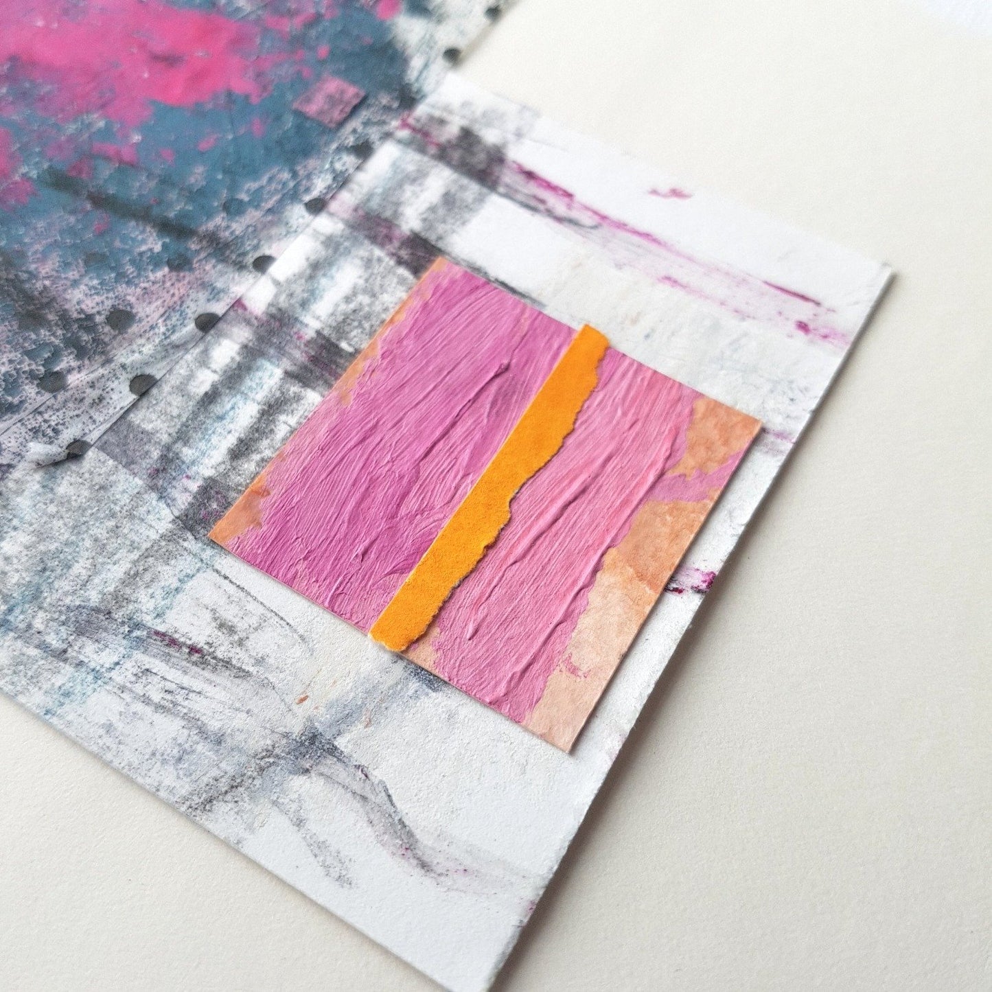 Close up of collage showing pink painted square and orange paper stripe.